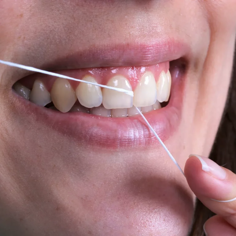 Pormenor da utilização de fio dentário entre os dentes.
