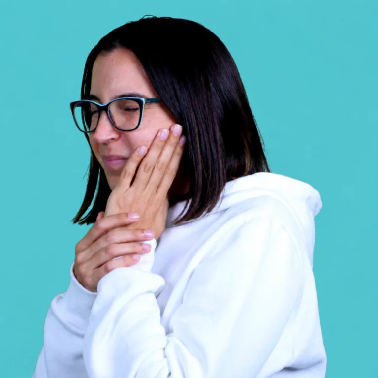 Mulher com a mão encostada à face e os olhos fechados.