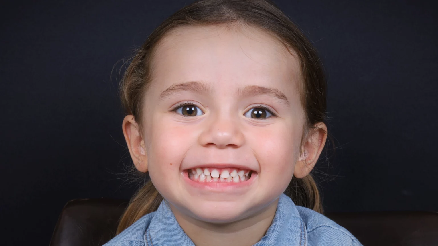 Criança a sorrir, com os dentes visíveis.