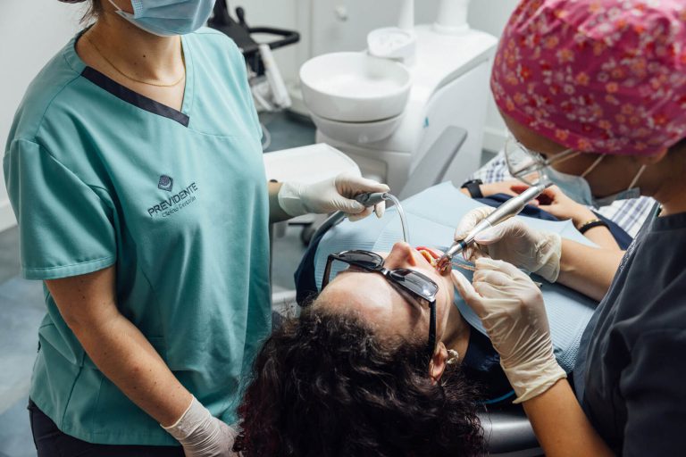 Duas profissionais com máscara e luvas durante um tratamento dentário.