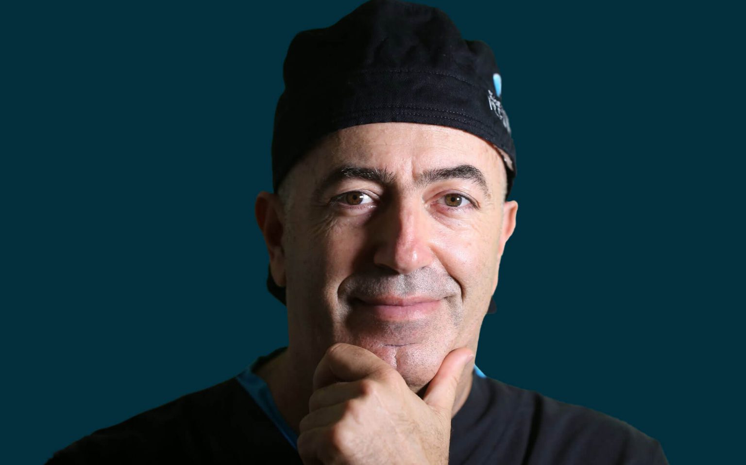 Retrato de um homem com touca preta e a mão sob o queixo.