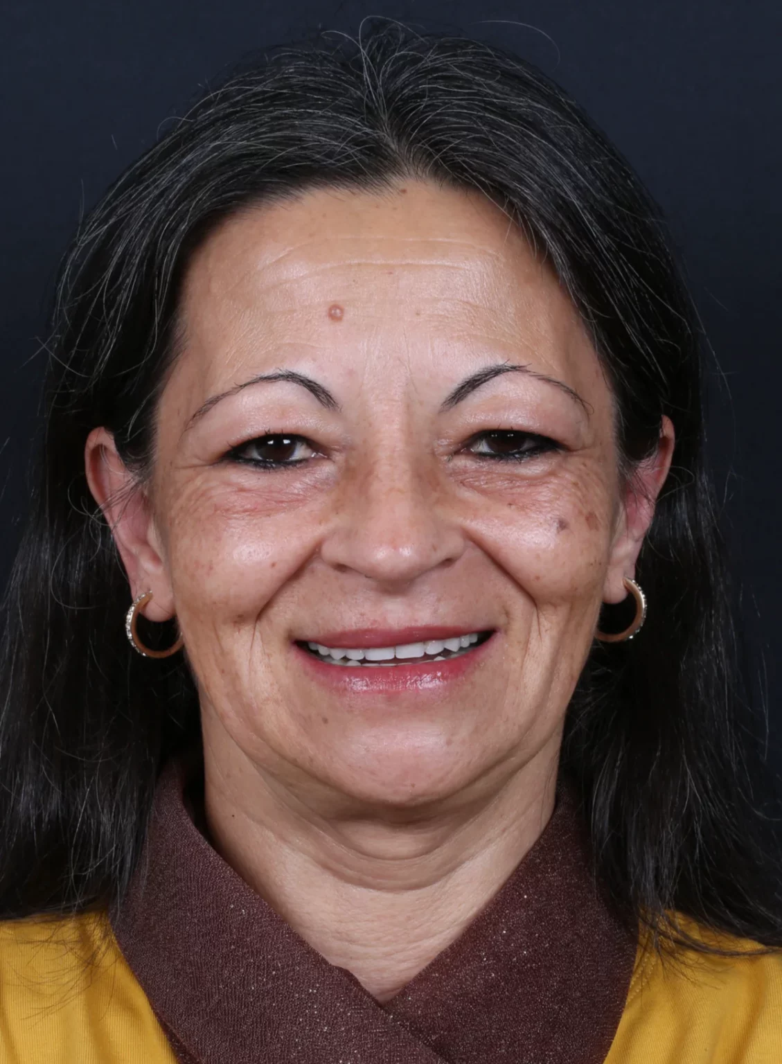 Retrato frontal de mulher de cabelo escuro, com os dentes da frente visíveis.