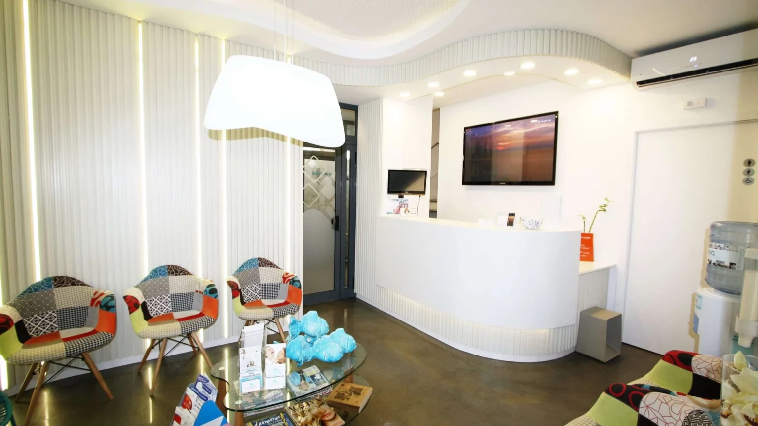 Recepção e sala de espera da clínica de Vilamoura, com cadeiras coloridas.