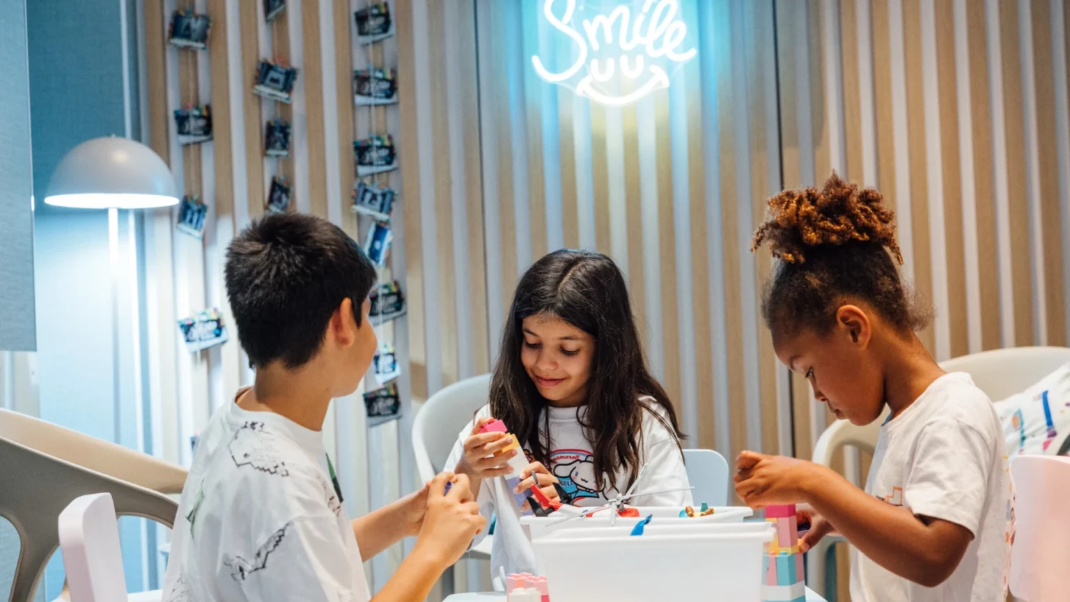 Três crianças a brincar à volta de uma mesa numa clínica dentária.