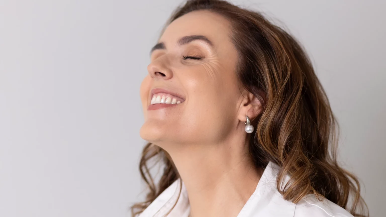 Mulher a sorrir de olhos fechados.
